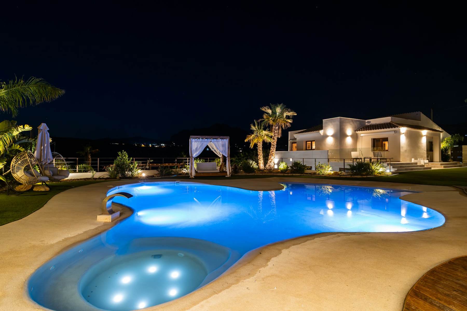 Luxe villa met verlichte pool in de avond